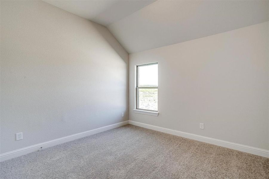 Carpeted spare room with vaulted ceiling