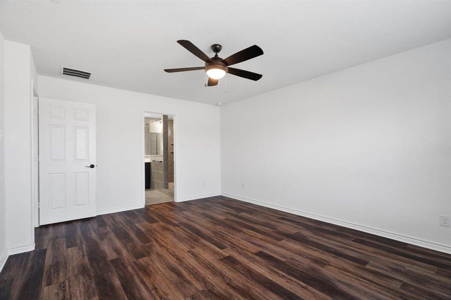 Unfurnished bedroom with dark hardwood / wood-style floors, ensuite bathroom, and ceiling fan