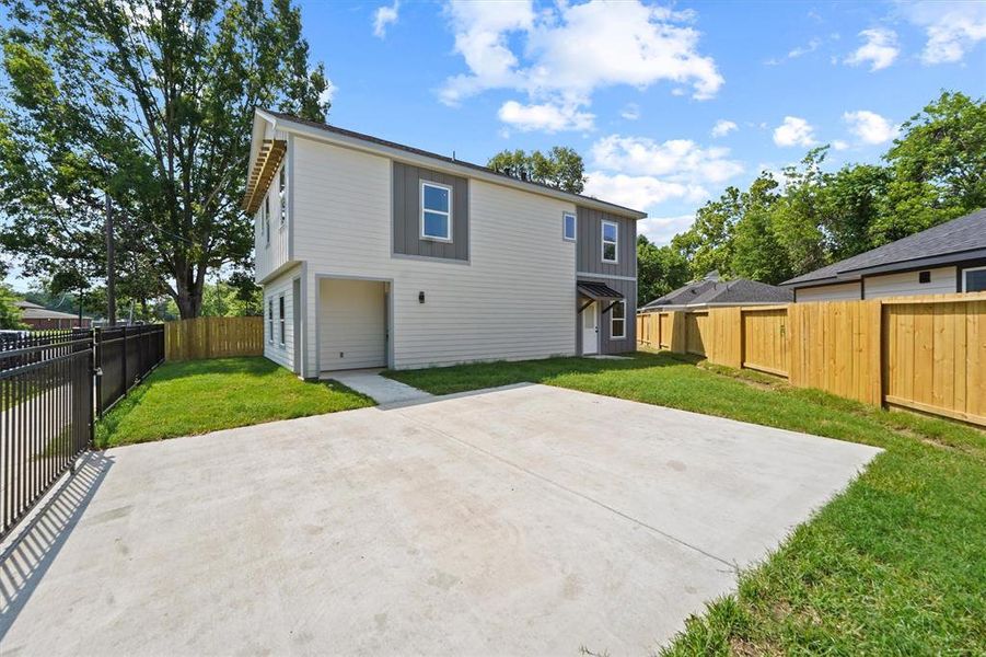 This is a two-story home featuring a fresh exterior with a spacious concrete driveway and an attached garage. The property includes a well-maintained lawn and a new wooden privacy fence, offering a secure and private outdoor space.