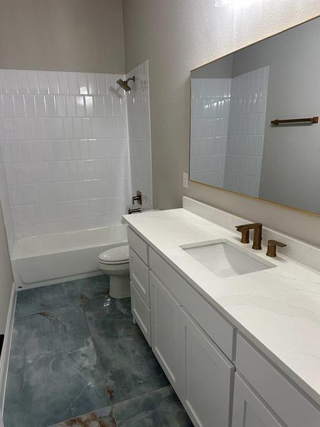 Full bathroom featuring vanity, tiled shower / bath combo, and toilet