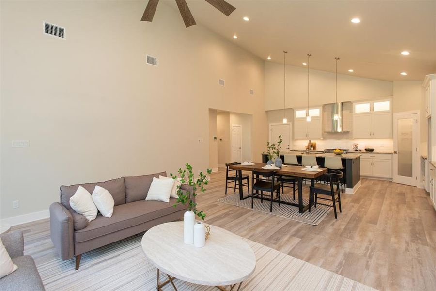 Living room with high vaulted ceiling, light wood-type flooring, and ceiling fan