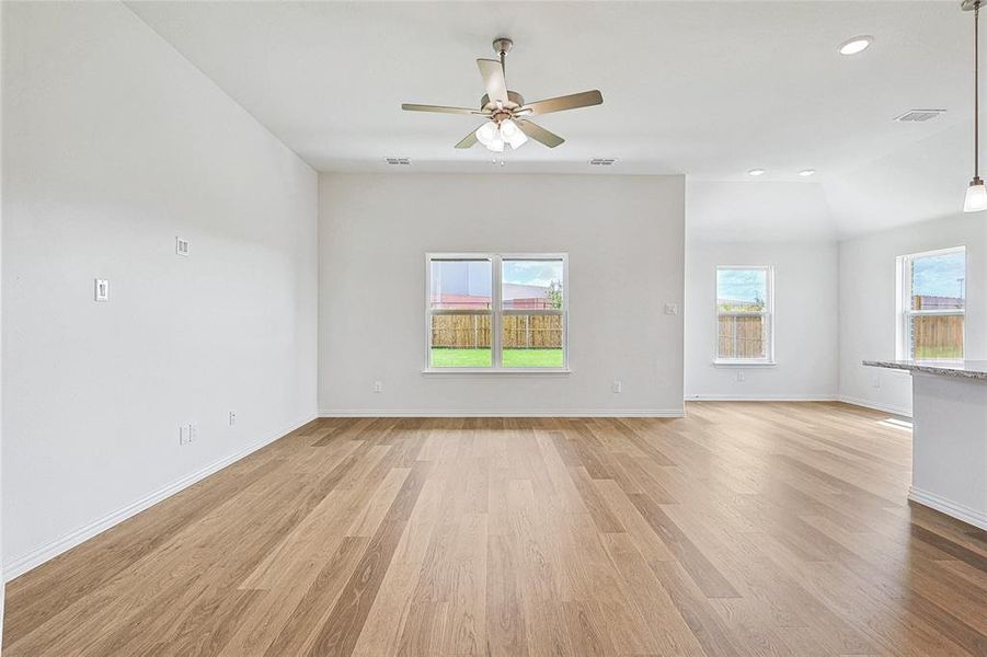 Unfurnished living room with ceiling fan, light wood-type flooring, and vaulted ceiling