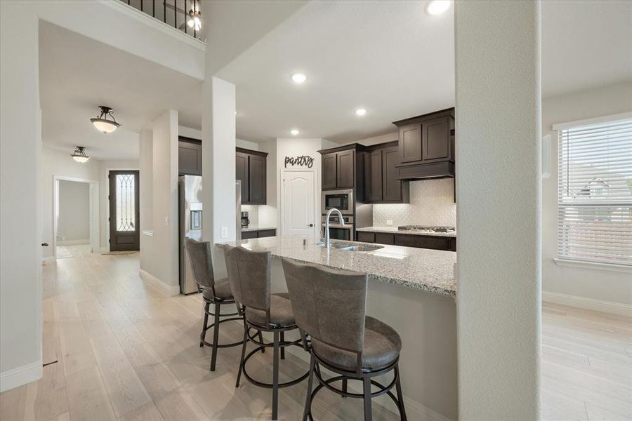 This kitchen features granite counters, tasteful backsplash, stainless steel appliances, dark brown 42 inch upgraded cabinets, and an undermount sink.