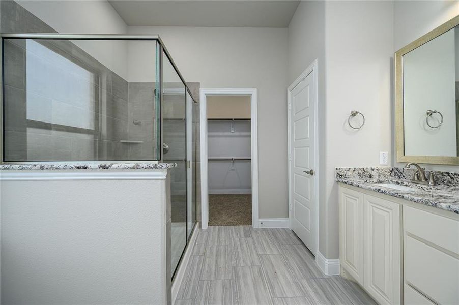 Bathroom featuring tile patterned flooring, a shower with shower door, and vanity