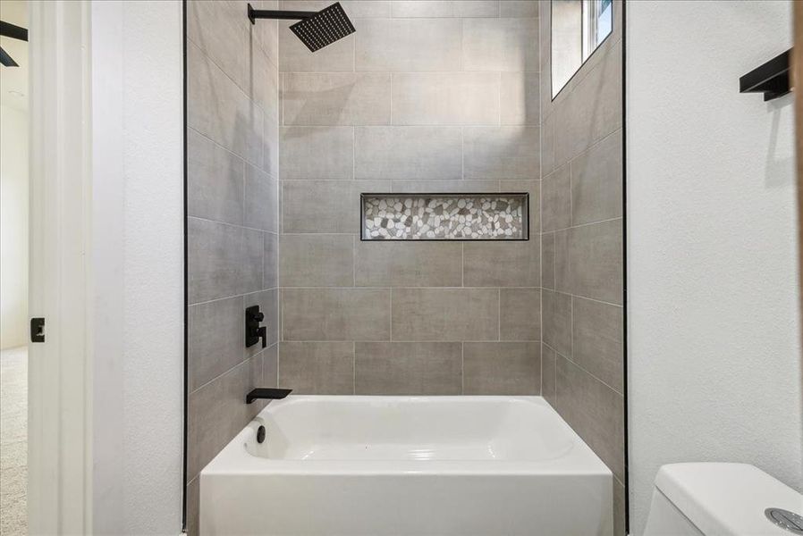 Bathroom with tiled shower / bath combo and toilet