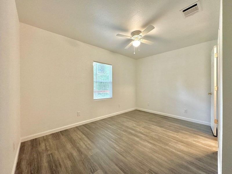 Empty room with hardwood / wood-style floors and ceiling fan