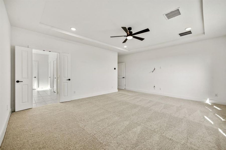 Unfurnished room with ceiling fan, a raised ceiling, and light carpet