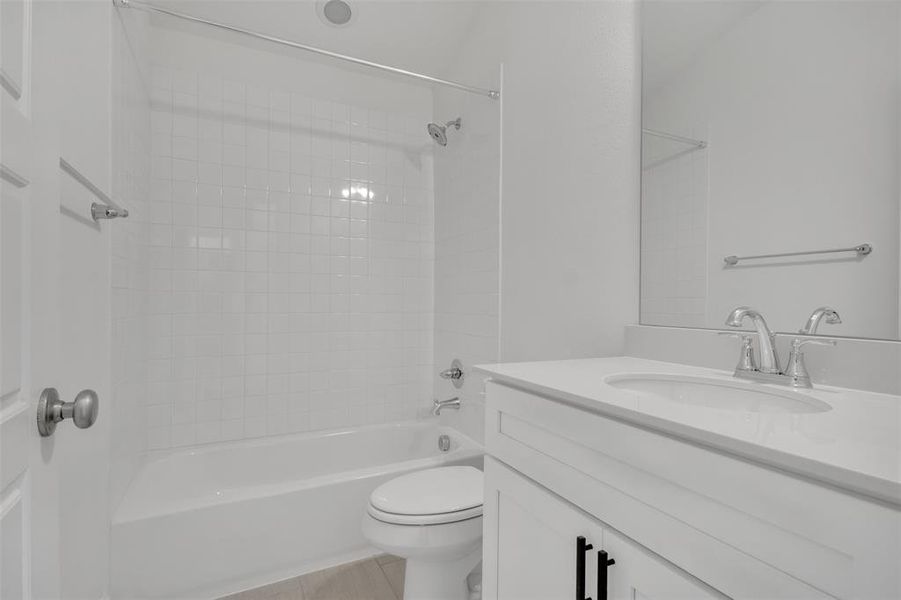 Full bathroom with tile flooring, tiled shower / bath, toilet, and vanity with extensive cabinet space