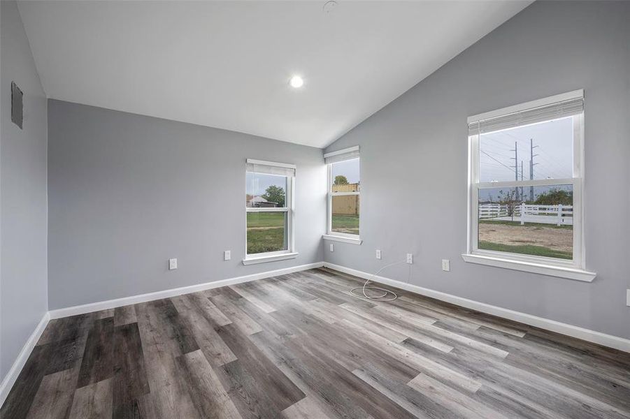 Unfurnished room with wood-type flooring and vaulted ceiling